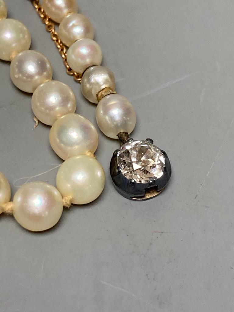 An early 20th century single strand graduated cultured? pearl necklace, with old cut diamond set white metal clasp, 42cm, gross weight 13.8 grams (string broken)